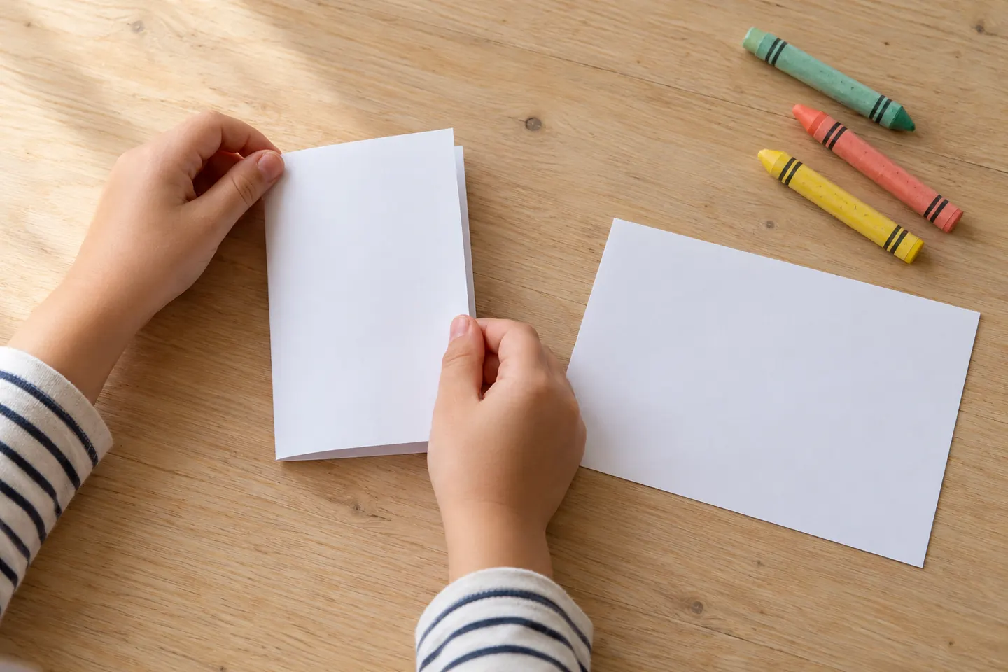 Hands align the short edges while folding one sheet in half.