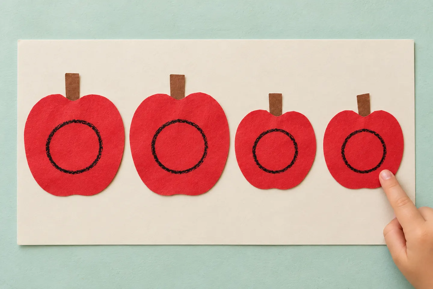 Four red paper apples ready to count one at a time.