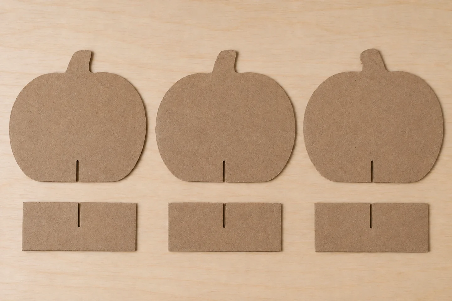 Three plain cardboard pumpkin shapes with bottom slits and three rectangular feet with matching top slits.
