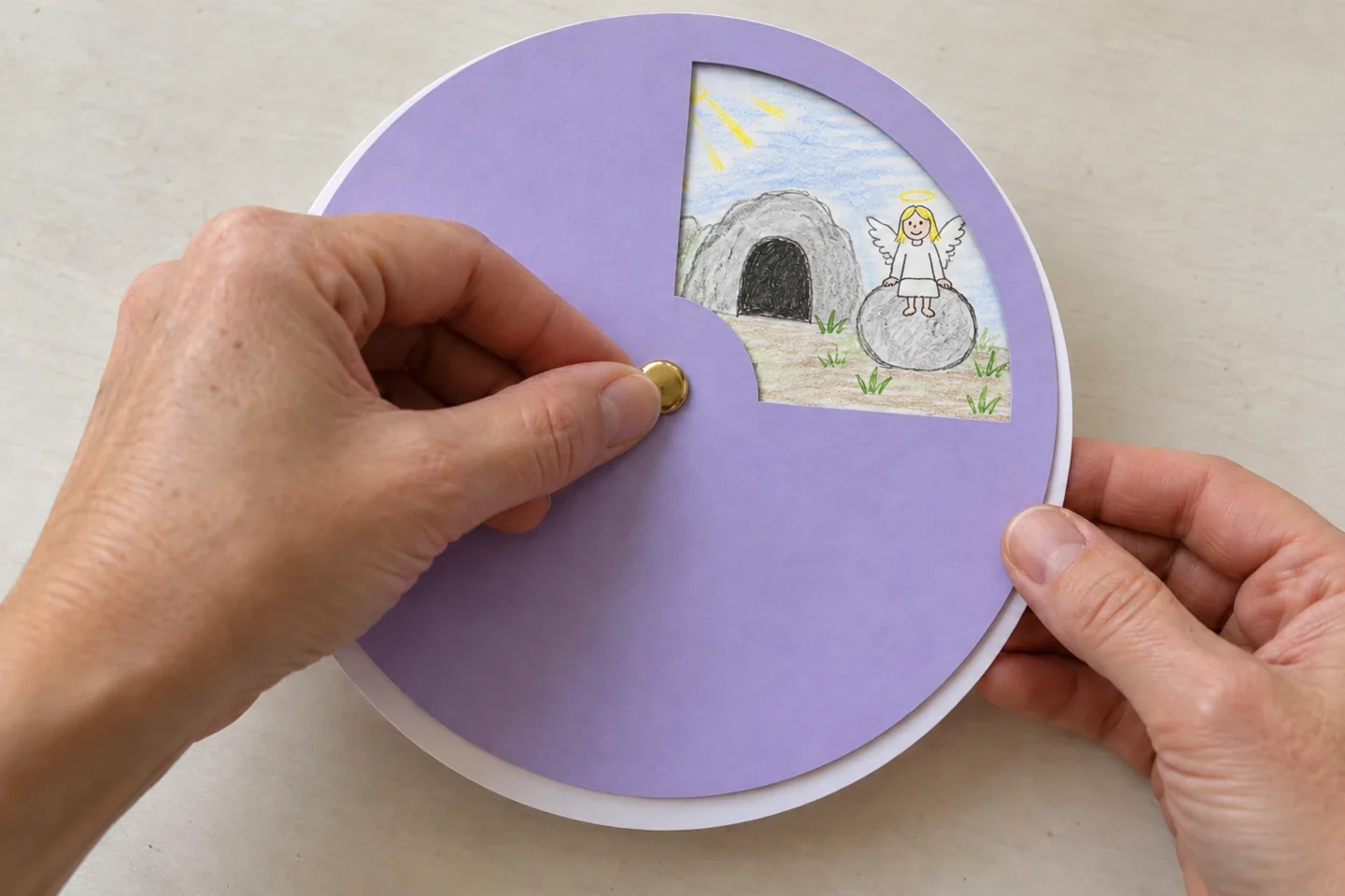 Adult hands fitting a single brass fastener through aligned central holes
