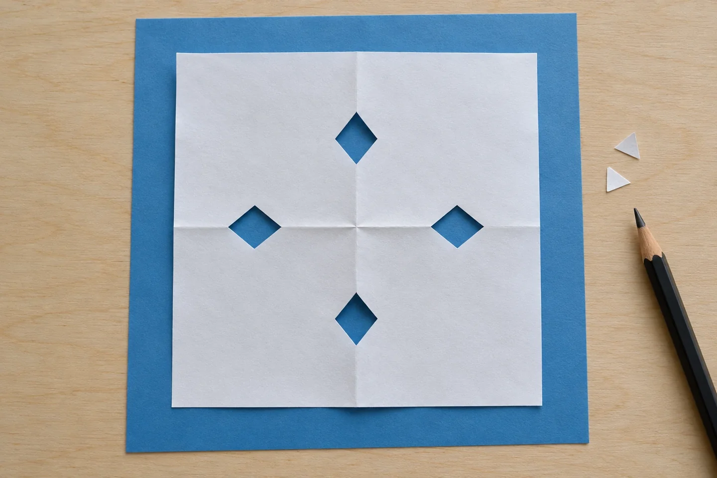 An opened square paper pattern with four diamond holes and intact connecting paper
