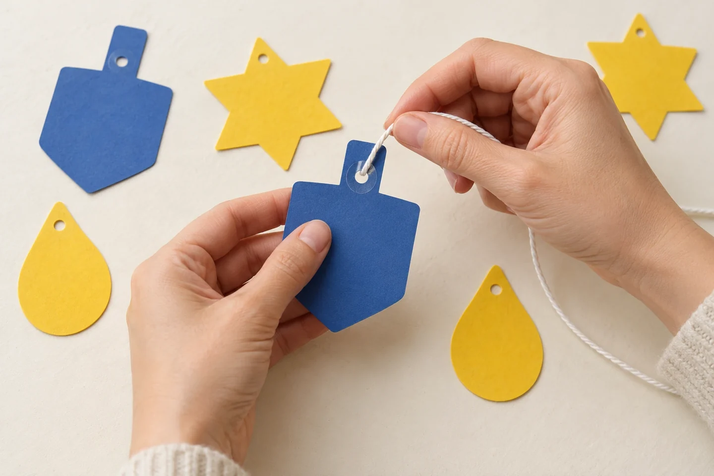 Cotton string passing through a reinforced hole in a paper dreidel shape