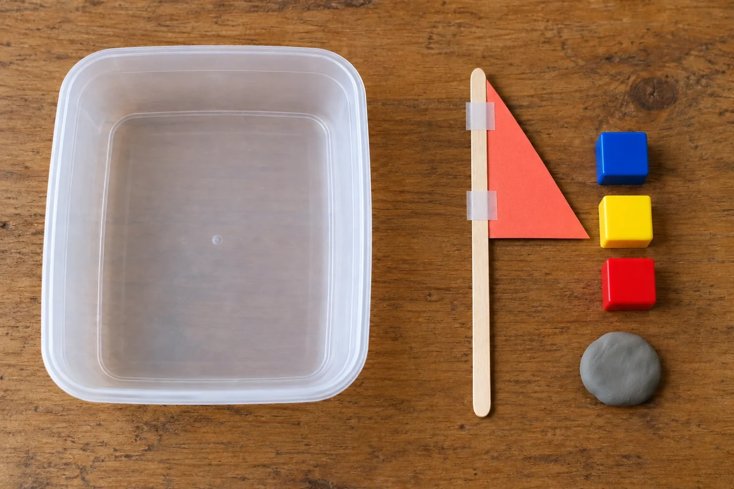 An 8 cm high coral cardboard triangle taped with two strips to the top half of a craft stick, laid flat next to empty container